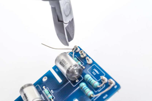 C10 and C11 styroflex (polystyrene) capacitors being installed on the D-12 PCB with alligator-clip heat sinks on the leads.